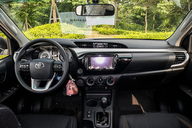 Toyota Hilux 2.4L chỉ có vô-lăng 3 chấu, Urethane cùng cách thiết kế khá đơn điệu khi nhìn khoang lái.